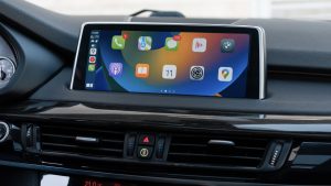 Ilustrasi ChatGPT CarPlay di dashboard mobil dengan logo Apple dan AI